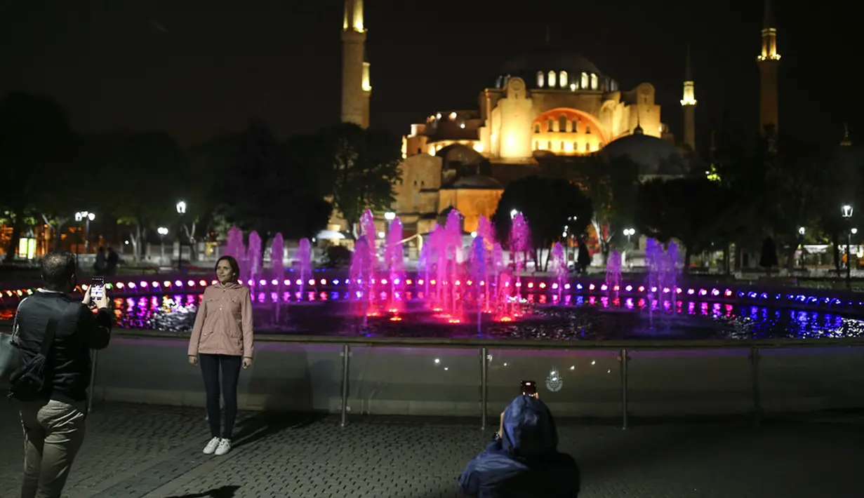 Warga berfoto dengan latar belakang Hagia Sophia era Bizantium di Distrik Sultanahmet, Istanbul, Turki, Kamis (29/4/2021). Presiden Turki Recep Tayyip Erdogan memberlakukan "penguncian penuh" hingga 17 Mei di tengah melonjaknya infeksi dan kematian akibat COVID-19. (AP Photo/Emrah Gurel)
