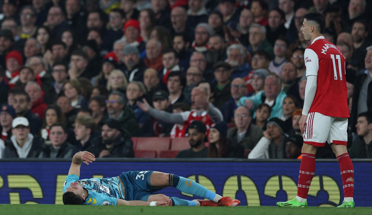 Bek Southampton, Jan Bednarek terbaring di lapangan setelah alami sedera usai berduel udara dengan Gabriel Martinelli (kanan) dalam laga Liga Inggris 2022/2023 di Emirates Stadium, London (21/4/2023). (AFP/Adrian Dennis)
