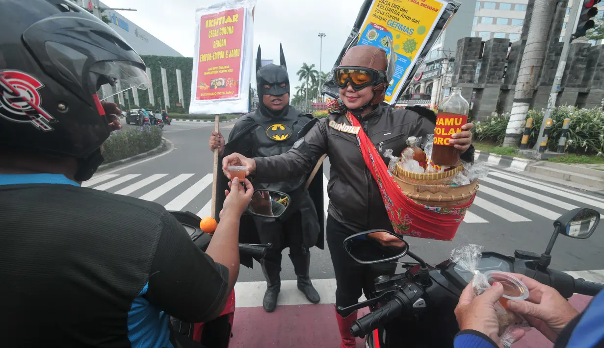 Warga mengenakan kostum superhero Gundala dan Batman menawarkan Jamu saat melakukan aksi sosialisasi pencegahan virus corona di Solo, Rabu (4/3/2020). Indonesia pada 2 Maret melaporkan kasus pertama virus corona yang menimpa dua warga Depok, Jawa Barat. (AFP Photo/Anwar Mustafa)