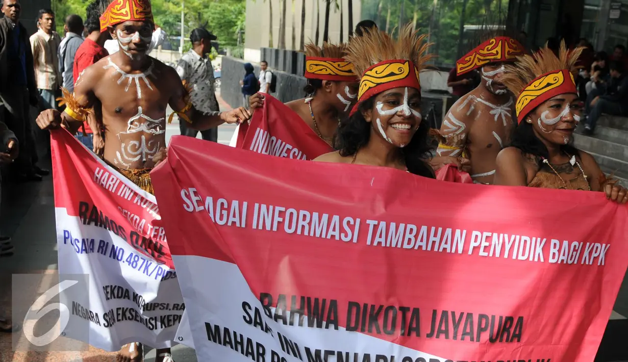 Sejumlah pemuda Papua mengenakan pakaian adat membawa spanduk berunjuk rasa di depan Gedung KPK, Jakarta, Senin (19/12). Mereka meminta KPK mengusut kasus korupsi pejabat yang mencalonkan diri pada Pilkada Jayapura 2017. (Liputan6.com/Helmi Affandi)