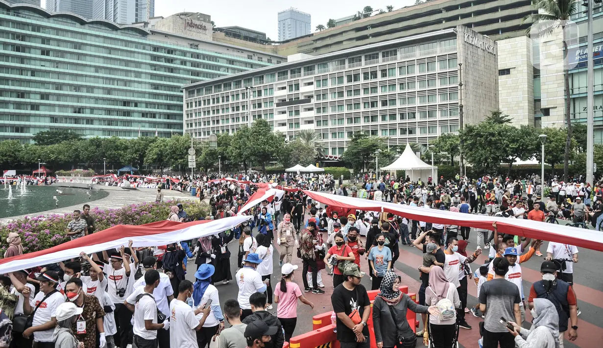 Peserta membentangkan bendera Merah Putih raksasa di kawasan Bundaran HI, Jakarta Pusat, Minggu (28/8/2022). Sebanyak 50.000 orang membentangkan bendera merah putih sepanjang 1.700 meter dari kawasan Monas hingga Bundaran HI yang merupakan rangkaian dalam memperingati Hari Kemerdekaan Indonesia dengan tema 'Pulih Lebih Cepat, Bangkit Lebih Kuat. (merdeka.com/Iqbal S Nugroho)