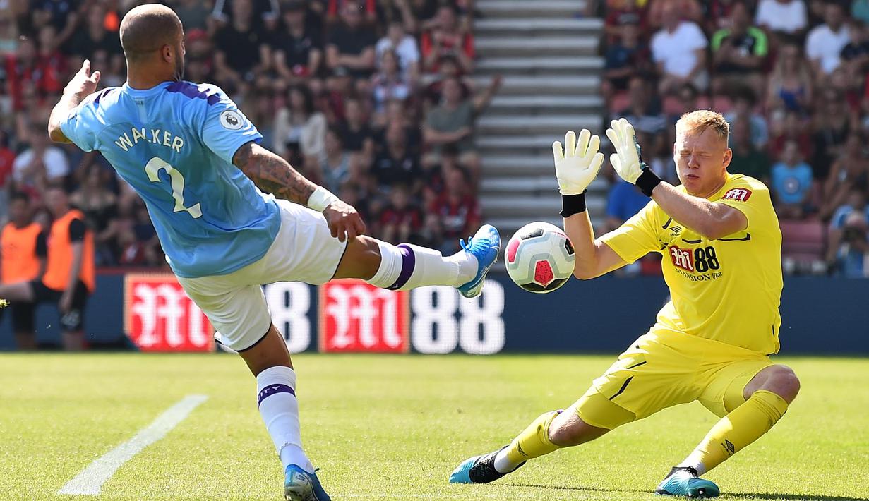 Kiper Bournemouth, Aaron Ramsdale, berusaha menahan bola tendangan Bek Manchester City, Kyle Walker, pada laga Premier League 2019 di Stadion Vitality, Minggu (25/8). Manchester City menang 3-1 atas Bournemouth. (AFP/Glyn Kirk)