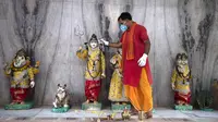 Seorang pendeta membersihkan patung Dewa Siwa dan dewa-dewa Hindu lainnya di sebuah kuil di Prayagraj, India, Senin (8/6/2020). India kembali membuka tempat ibadah, pusat perbelanjaan, dan restoran setelah tiga bulan lockdown karena pandemi virus corona COVID-19. (AP Photo/Rajesh Kumar Singh)