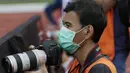 Seorang fotografer menggunakan masker saat meliput pertandingan PSM Makassar melawan Kaya FC-Iloilo pada laga penyisihan Grup H Piala AFC di Stadion Madya, Jakarta, Selasa (10/3/2020). (Bola.com/M Iqbal Ichsan)