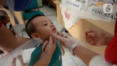 Bidan dibantu Kader Posyandu memberikan vaksin vitamin A dan imunisasi di Posyandu RW 20, Kelurahan Pondok Benda, Tangerang Selatan, Selasa (18/8/2020). Pemerintah sudah mengaktifkan pelayanan posyandu ketiga sejak pandemi Covid-19 dengan memperketat protokol kesehatan. (merdeka.com/Dwi Narwoko)