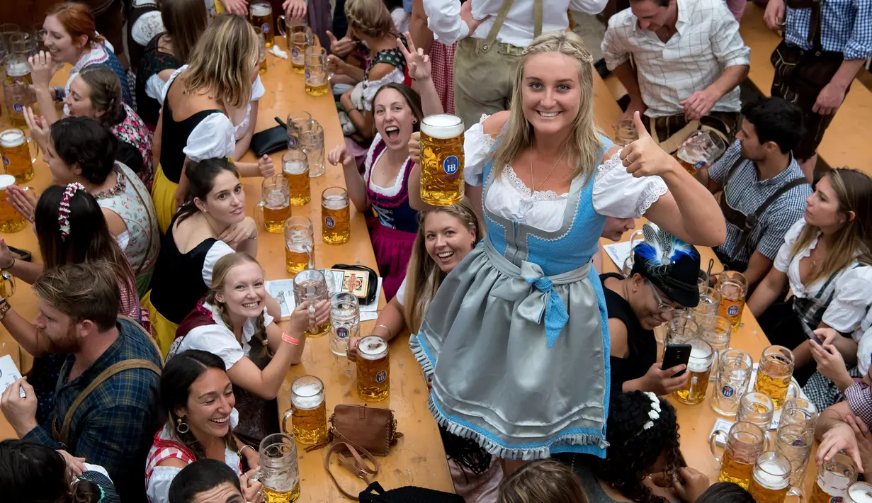 Seorang wanita menunjukkan gelas berisi bir bersama rekan-rekannya saat mengikuti festival minum bir tahunan dalam pembukaan Oktoberfest ke-182 di Munich, Jerman (16/9). (AFP Photo/dpa/Sven Hoppe/Germany Out)