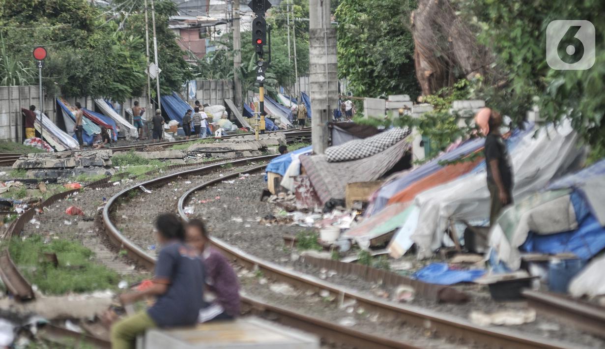 Sejumlah tunawisma beraktivitas di dekat gubuknya yang berada di bantaran rel kereta api kawasan Senen, Jakarta, Minggu (14/2/2021). Setelah sempat ditertibkan, puluhan bangunan semipermanen yang beratapkan terpal dan beralas kardus milik tunawisma kembali menjamur. (merdeka.com/Iqbal S. Nugroho)