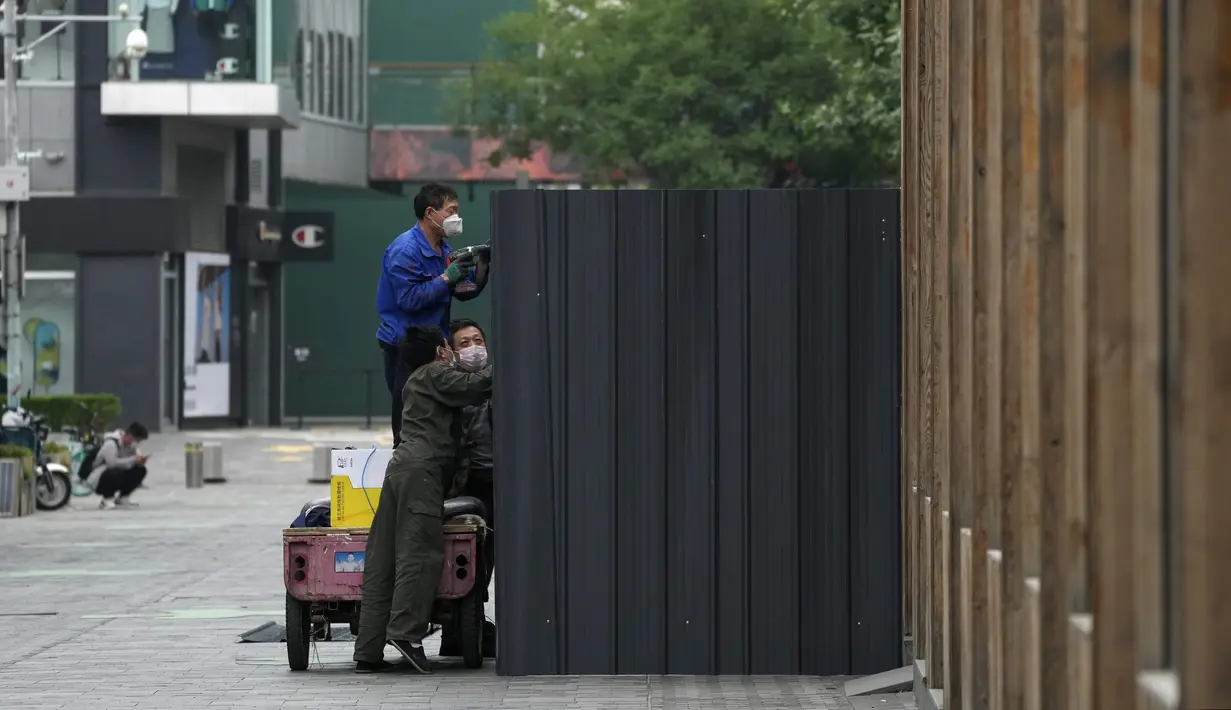 <p>Pekerja yang mengenakan masker memasang penghalang logam di lingkungan yang telah dikunci sebagai bagian dari pengendalian COVID-19 di Beijing, Senin (13/6/2022). Pejabat kesehatan kota mengatakan sejauh ini ada 166 kasus yang dikonfirmasi terkait dengan wabah yang dimulai di bar Heaven Supermarket di daerah Sanlitun pada Kamis, 9 Juni 2022. (AP Photo/Andy Wong)</p>