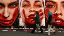 Warga berjalan disamping deretan foto wanita dengan wajah bercat merah di Sao Paulo Art Museum, Brasil , 10 Juni 2016. Ini juga sebagai protes organisasi non -pemerintah yang dinamakan Rio de Paz. (REUTERS / Paulo Whitaker)