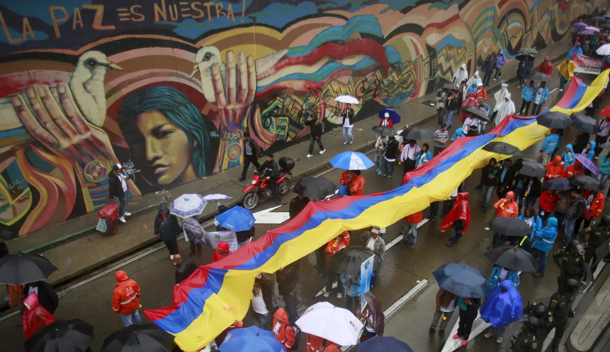 Demonstran membentangkan bendera Kolombia saat menggelar aksi mogok nasional di Bogota, Kolombia, (17/3). Aksi tersebut merupakan protes terhadap sejumlah kebijakan pemerintah. (REUTERS/John Vizcaino)