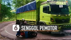 Sebuah truk besar senggolan dengan sepeda motor di jalan tikungan.