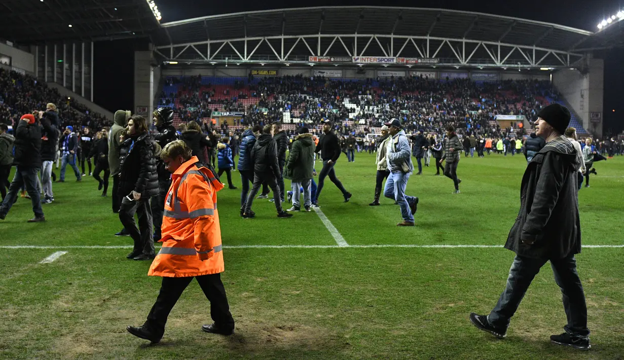 Keributan terjadi setelah Manchester City dikalahkan Wigan 0-1 pada babak kelima Piala FA di Stadion DW, Senin (19/2). Begitu peluit akhir dibunyikan wasit, suporter Manchester City tampak marah. (Oli SCARFF/AFP)