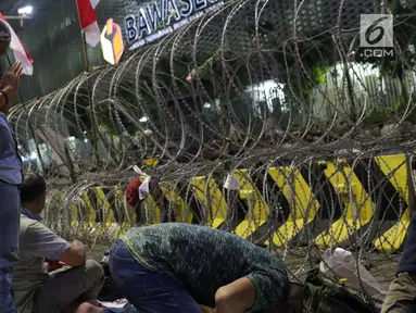 Peserta aksi massa Gerakan Nasional Kedaulatan Rakyat melakukan salat maghrib saat unjuk rasa di depan Gedung Bawaslu, Jalan MH Thamrin, Jakarta, Selasa (21/5/2019). Dalam aksinya, mereka Bawaslu memeriksa hasil Pemilu 2019 yang dinilai banyak terdapat kecurangan. (Liputan6.com/Helmi Fithriansyah)