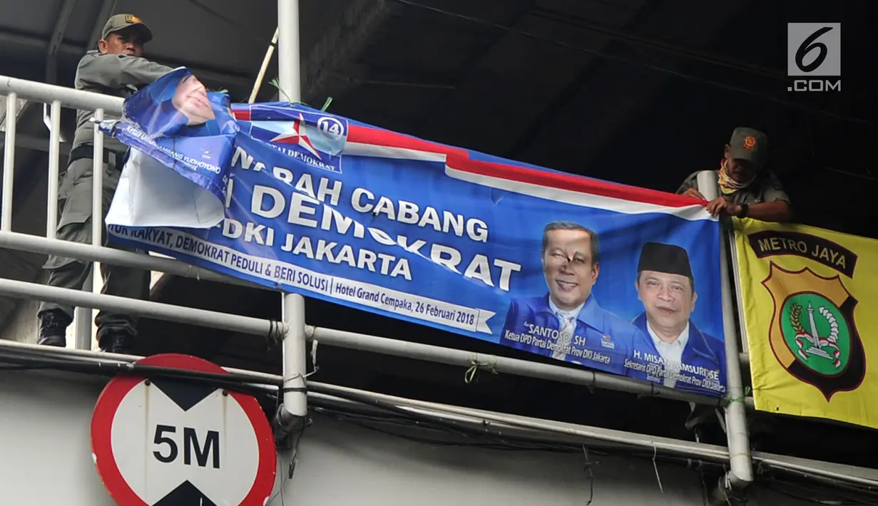 Petugas Satpol PP membongkar spanduk parpol yang dipasang di Jalan Letjen Suprapto, Cempaka Putih, Jakarta (21/3). Panwaslu Cempaka Putih menertibkan spanduk tersebut karena melanggar UU Nomor 7 Tahun 2017 tentang Pemilihan Umum. (Merdeka.com/Arie Basuki)