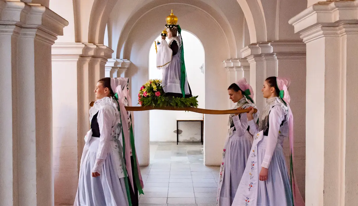 Sejumlah remaja mengenakan pakaian tradisional Sorbs memikul patung Bunda Maria saat mengikuti prosesi Whit Monday di gereja di Rosenthal, Jerman (21/5). Prosesi tradisional ini di gelar di dekat perbatasan Jerman-Polandia. (AP Photo / Jens Meyer)