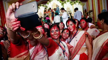 Wanita Hindu berselfie didekat patung dewi Durga pada hari terakhir festival Durga Puja di Mumbai, India (11/10). Festival ini semakin populer pada masa Kemaharajaan Britania di Bengali. (AP Photo/Rajanish Kakade)