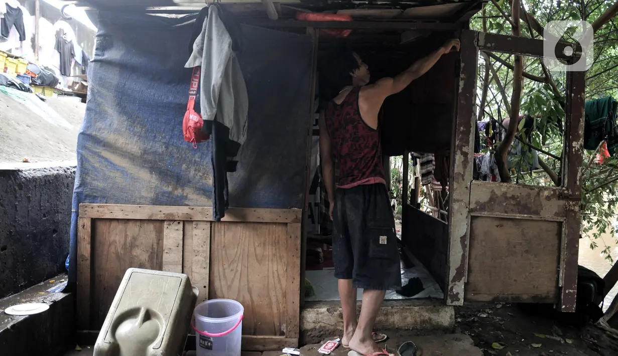 Warga bantaran menunjukkan ketinggian banjir yang merendam hingga pintu gubuk. Banjir tersebut juga menyebabkan gubuk mereka semakin rapuh dan dipenuhi sampah serta menghanyutkan barang-barang hasil pulung. (merdeka.com/Iqbal S Nugroho)