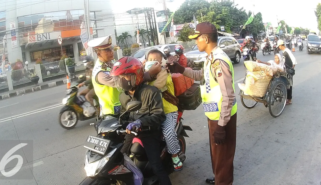 Petugas Kepolisian memberikan masker untuk balita di Simpang Maya, Tegal, Jawa Tengah Minggu (10/7). Pihak Kepolisian menghimbau kepada pengendara motor supaya berhati-hati dalam berkendara. (Liputan6.com/Herman Zakharia)