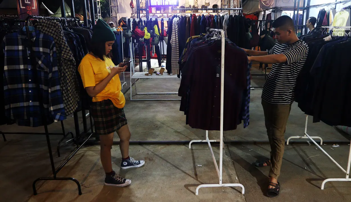 Pengunjung melihat-lihat produk merek pakaian di Jakcloth Indonesian Pride 2018, Jakarta, Rabu (19/12). Tahun ini, ada 380 clothing brand lokal yang menggelar sale dengan diskon sampai 70 persen. (Liputan6.com/JohanTallo)