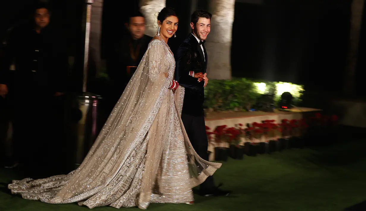 Aktris Bollywood Priyanka Chopra dan musisi AS Nick Jonas berjalan saat resepsi pernikahan mereka di New Delhi, India, Selasa (4/12). Keduanya resmi menikah pada 1 Desember 2018. (AP Photo/Altaf Qadri)