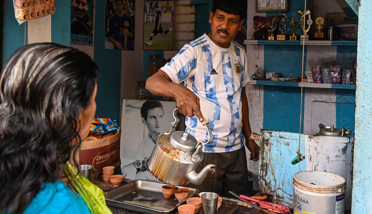 Pemilik warung teh, Shib Shankar Patra sebagai fans timnas Argentina mengenakan jersey saat bekerja di dalam warung tehnya yang dicat dengan warna tim di Ichhapur sekitar 35 km sebelah utara Kolkata pada 12 Desember 2022. Argentina berhasil lolos ke babak semifinal Piala Dunia 2022 Qatar yang akan melawan Kroasia. (AFP/Dibyangshu Sarkar)