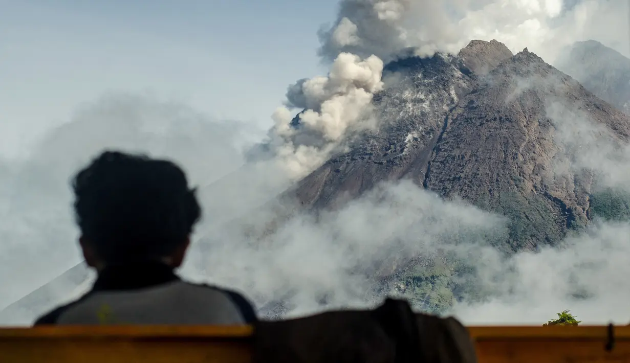 Seorang warga melihat Gunung Merapi dari Sleman, 2 Desember 2021. Warga diminta mewaspadai potensi dampak guguran lava dan awan panas Gunung Merapi di sektor selatan-barat daya yang meliputi Sungai Kuning, Boyong, Bedog, Krasak, Bebeng, dan Putih. (AGUNG SUPRIYANTO/AFP)