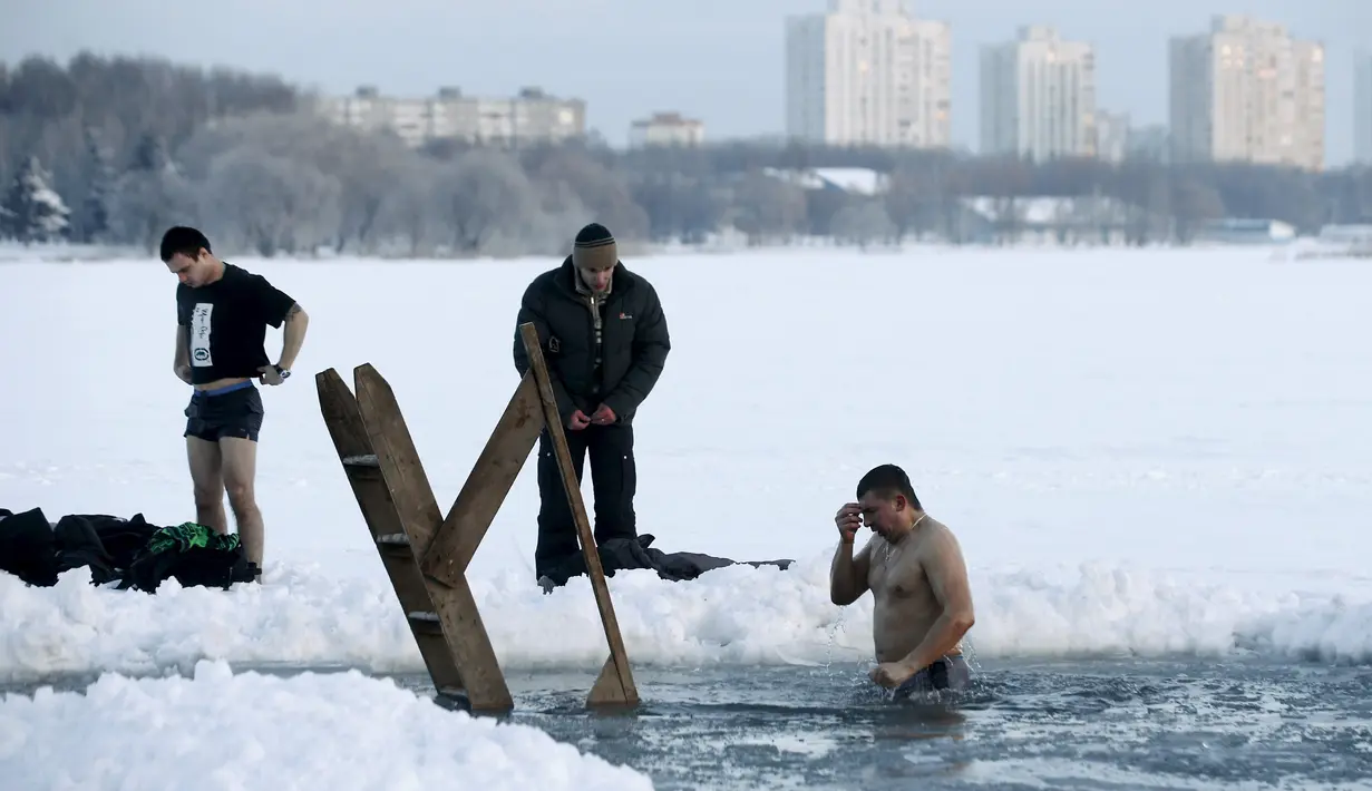 Seorang pria mandi di danau es saat prosesi perayaan Epifani Ortodoks di Minsk, Belarusia (19/1/2016). Perayaan ini diwajibkan mandi dalam kolam berisi air suci, dalam kondisi cuaca apapun. (REUTERS/Vasily Fedosenko)