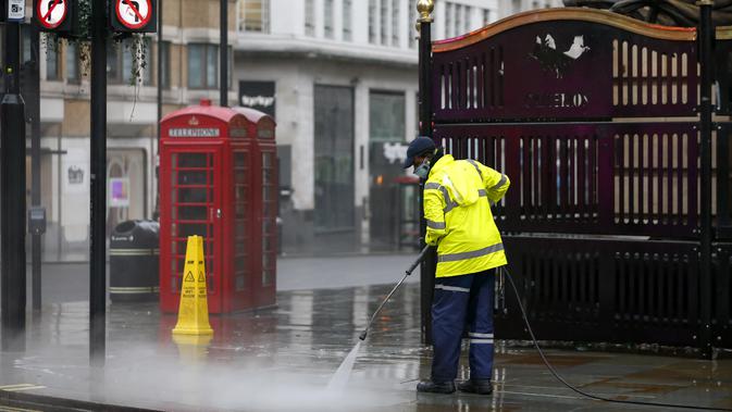 Seorang pekerja membersihkan jalan dekat Leicester Square, London, Inggris, 21 Desember 2020. Menteri Kesehatan Inggris Matt Hancock mendesak warga Inggris untuk berperilaku seolah-olah mereka sudah terjangkit virus corona COVID-19. (Xinhua/Han Yan)
