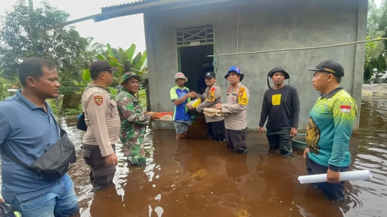 Kapolsek Siak Kecil Ipda Eko Wahyu bersama personel dan TNI serta aparatur desa menyerahkan bantuan sembako kepada korban bencana banjir.