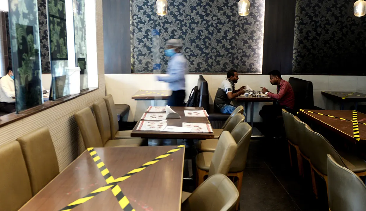 Orang-orang duduk dengan menjaga jarak di sebuah restoran yang dibuka kembali usai pelonggaran lockdown di Chennai, India, Senin (8/6/2020). Fase kelima karantina wilayah (lockdown) dimulai pada 1 Juni di India, dengan sejumlah pelonggaran untuk membuka kembali kegiatan ekonomi. (Arun SANKAR / AFP)