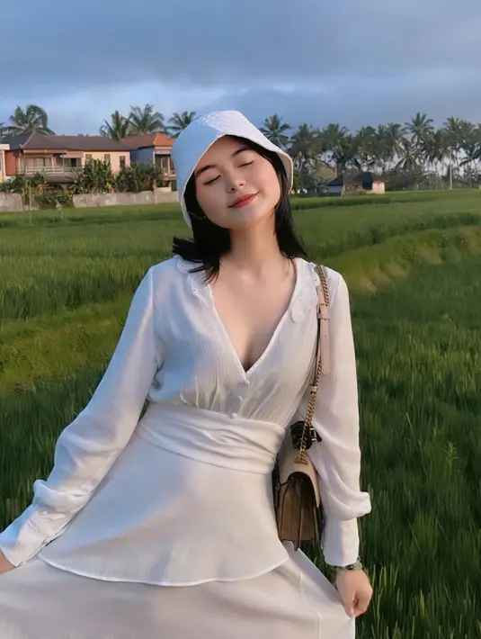 Berpose dengan latar pemandangan sawah, Cesen tampak menawan dengan dress putih dan bucket hat. [Foto: Instagram/ceseniy].