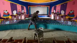 Pekerja membersihkan ruang bioskop sebagai persiapan kemungkinan pembukaan kembali setelah pelonggaran pembatasan Covid-19, di Chennai, Sabtu (3/10/2020). Kementerian Kesehatan India melaporkan pada Sabtu (3/10) total kematian di India akibat virus corona naik menjadi 100,842. (Arun SANKAR/AFP)