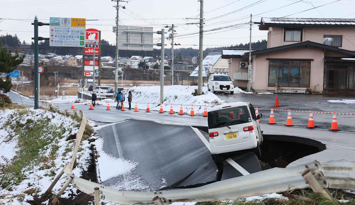 Sebuah kendaraan terparkir di tepi jalan yang runtuh di Kota Tohoku, Prefektur Aomori, Jepang, pada Selasa 9 Desember 2025. Gempa besar mengguncang lepas pantai utara Jepang. (JIJI Press/Japan OUT/AFP)