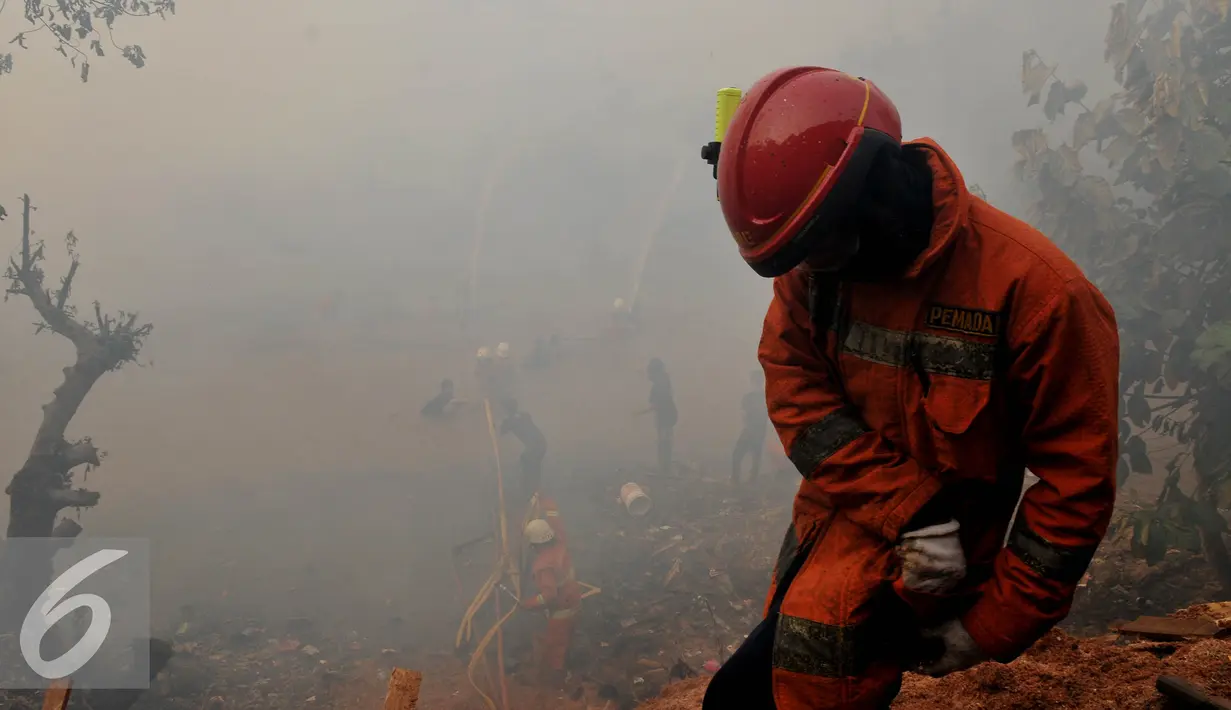 Petugas pemadam berupaya menyemprotkan air saat terjadinya kebakaran yang melanda rumah hunian semi permanen di bantaran sungai anak kali Ciliwung,  Jakarta, Rabu (2/9/2015). Penyebab kebakaran tersebut belum di ketahui. (Liputan6.com/Johan Tallo)