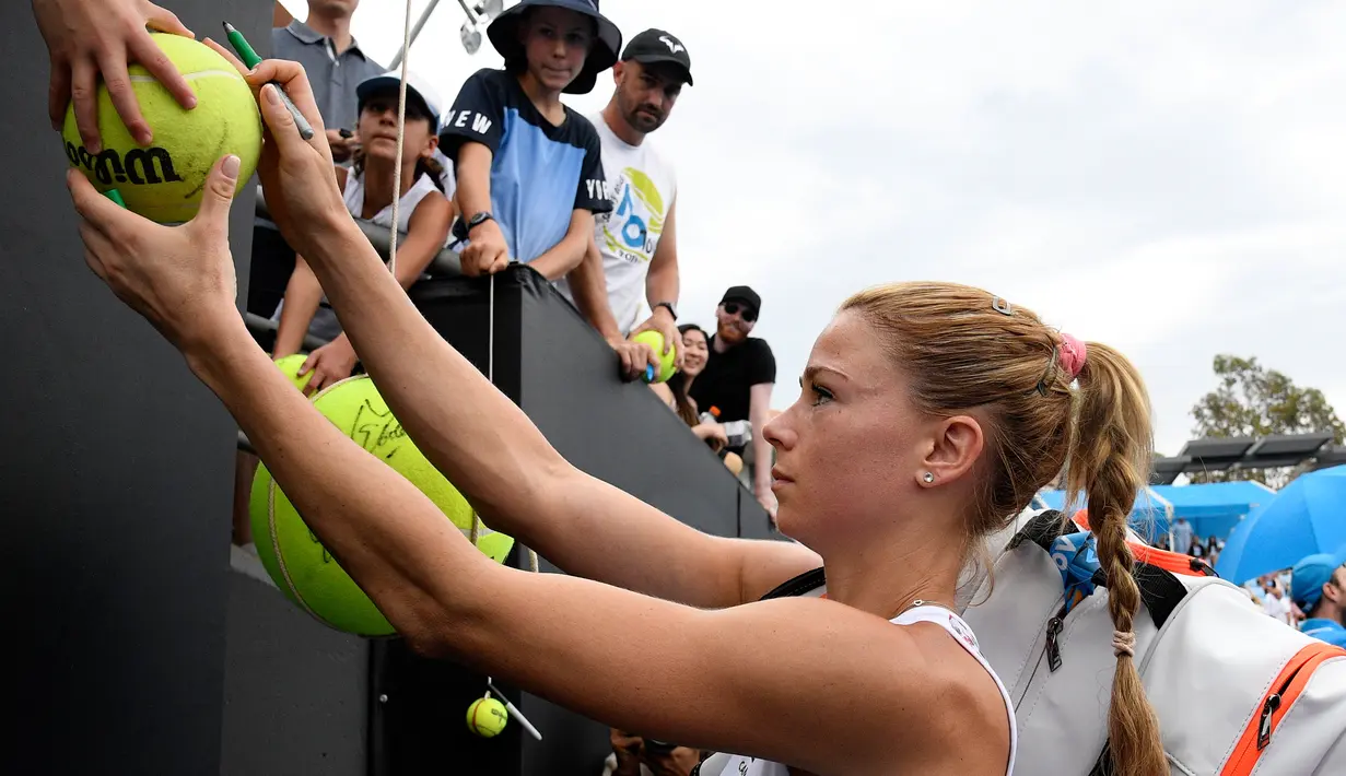 Petenis Italia, Camila Giorgi menandatangi bola yang disodorkan penggemarnya setelah menang atas Iga Swiatek dari Polandia pada pertandingan putaran kedua turnamen Australia Terbuka di Melbourne, Kamis (17/1). (AP Photo/Andy Brownbill)
