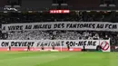 Suporter FC Metz membentangkan spanduk bertulisakan "Saat Anda hidup bersama hantu FC Metz, Anda sendirilah yang menjadi hantu" pada laga lanjutan Liga Prancis 2023/2024 melawan RC Lens di Saint-Symphorien Stadium, Longeville-les-Metz, Prancis, Sabtu (13/04/2024) dini hari WIB. (AFP/Jean-Christophe Verhaegen)