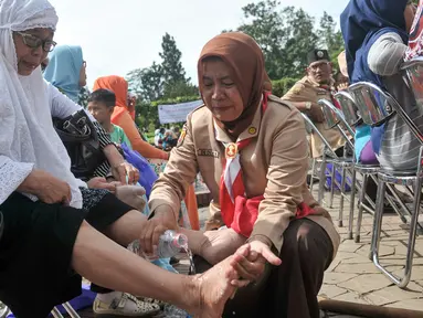 Pembina anggota Kwarnas Gerakan Pramuka menangis sambil membasuh kaki ibunya di Taman Wiladatika Cibubur, Jakarta, Rabu (21/12). Aksi massal membasuh kaki ibu itu dalam rangka memperingati Hari Ibu 2016. (Liputan6.com/Yoppy Renato)