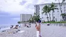 Berada di pantai Hawaii, Syahrini mengenakan atasan lengan coklat dipadukan celana putih. Ia mengenakan topi hitam. [Instagram/@princessyahrini]