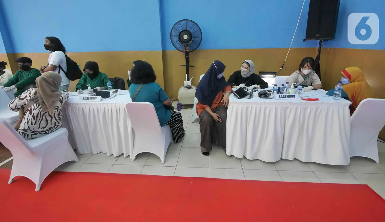 Petugas mengecek kesehatan warga saat gelaran Vaksin Covid-19 Serentak di GOR Radio Dalam, Jakarta Selatan, Selasa (8/3/2022). Vaksinasi serentak digelar di seluruh Indonesia yang diselenggarakan Kepolisian RI dengan target penyaluran vaksin sebanyak 1.114.750 dosis. (Liputan6.com/Herman Zakharia)