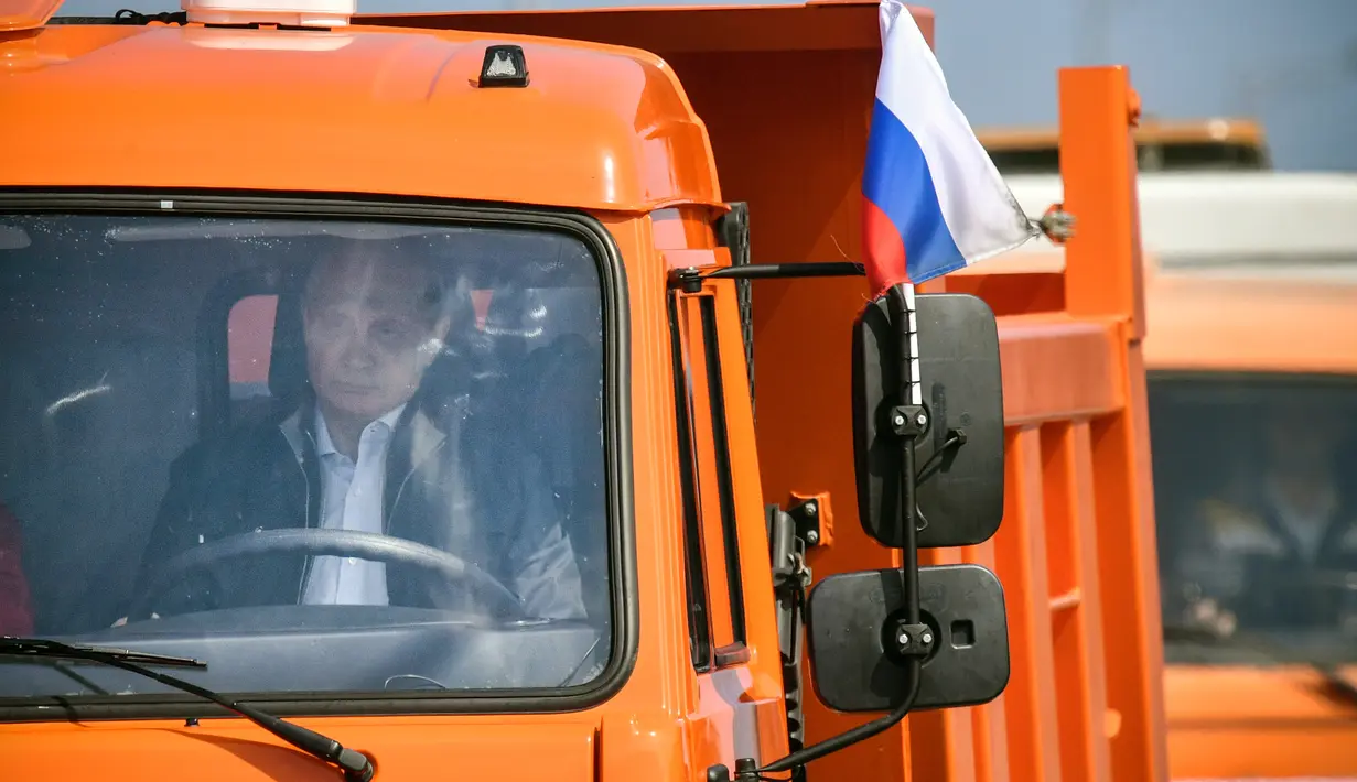 Presiden Rusia, Vladimir Putin mengemudikan truk saat secara resmi membuka jembatan baru yang menghubungkan wilayah Rusia dan Semenanjung Crimea di dekat Kerch, Selasa (15/5). Jembatan ini menjadi yang terpanjang di Rusia. (Alexander Nemenov/Pool via AP)