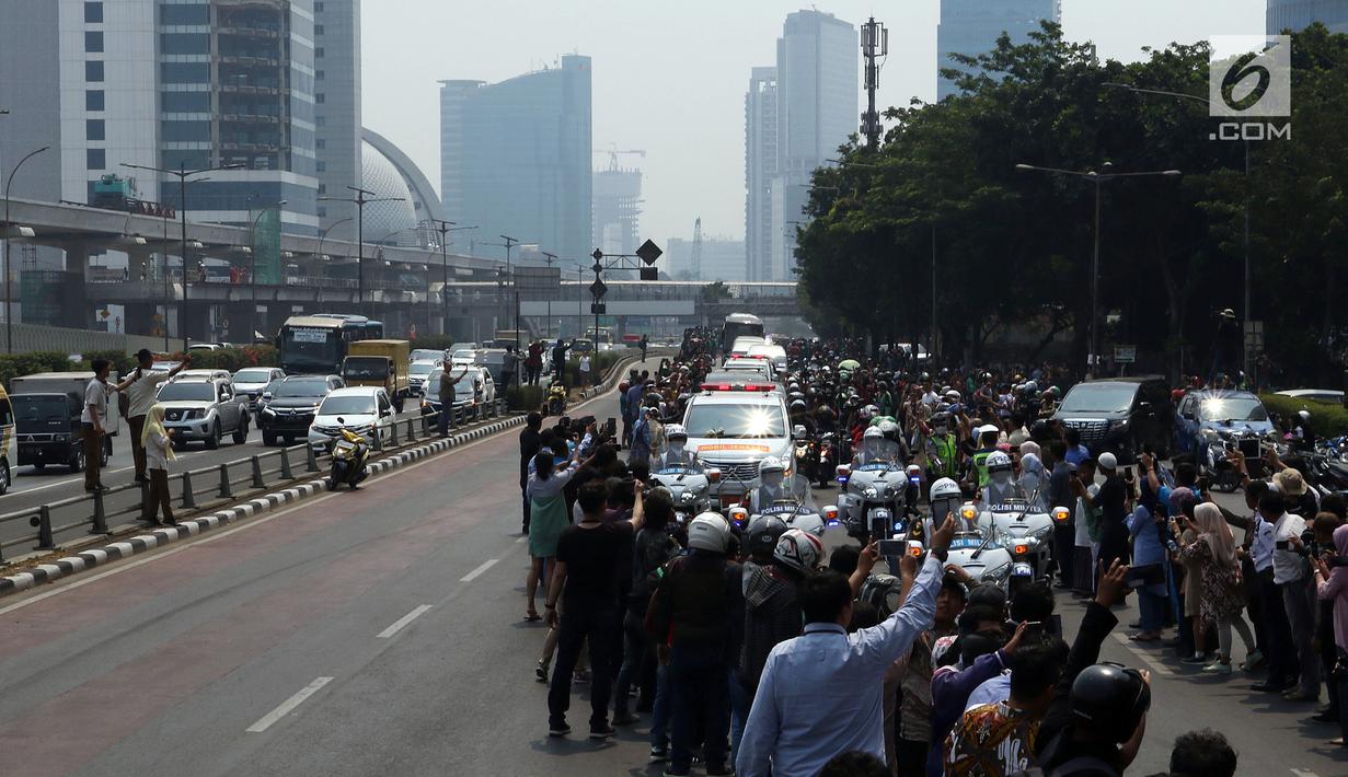 Warga mengambil gambar iring-iringan mobil jenazah yang membawa almarhum Presiden ke-3 RI, BJ Habibie saat melintasi Jalan Gatot Subroto menuju TMP Kalibata, Jakarta, Kamis (12/9/2019). BJ Habibie meninggal pada Rabu (11/9/2019) setelah menjalani perawatan di RSPAD. (Liputan6.com/Johan Tallo)
