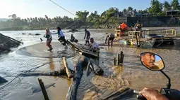 Untuk menyeberangi Sungai Peusangan Bireuen Aceh, warga terpaksa menggunakan rakit kayu sederhana yang ditarik dengan tali atau kabel baja (seling). Tampak dalam foto, masyarakat menggunakan rakit tali untuk menyeberangi Sungai Peusangan menyusul banjir bandang yang menghancurkan desa-desa di sekitarnya di Kabupaten Bireuen, provinsi Aceh, pada Senin 5 Januari 2026. (CHAIDEER MAHYUDDIN/AFP)