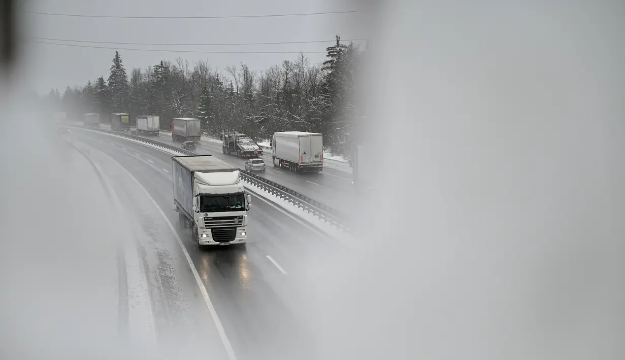 Truk melaju di jalan raya saat hujan salju, dekat kota Unec, Slovenia, pada Senin (23/1/2023). Hujan salju lebat dan angin kencang menghambat lalu lintas dan menyebabkan pemadaman listrik di seluruh Slovenia. (Jure Makovec / AFP)
