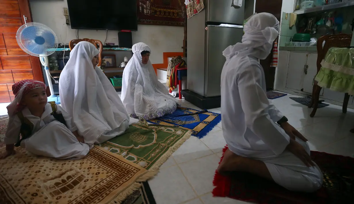 Keluarga muslim melaksanakan salat Idul Fitri di rumah mereka di Manila, Filipina, Minggu (24/5/2020). Pemerintah Filipina melarang pertemuan massal termasuk di masjid dan gereja untuk menahan penyebaran virus corona COVID-19. (Photo by - / AFP)