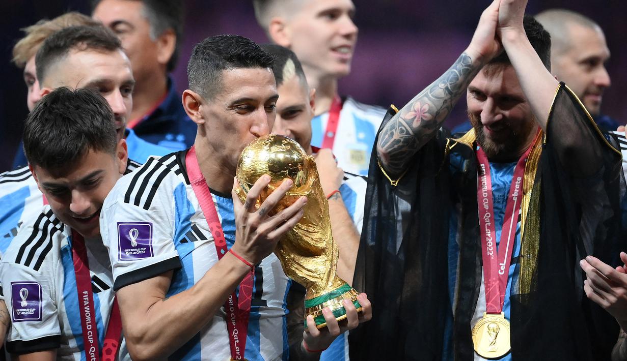 <p>Gelandang Timnas Argentina, Angel Di Maria mencium trofi Piala Dunia dalam perayaan kemenangan usai mengalahkan Prancis pada partai final Piala Dunia 2022 di Lusail Stadium, Doha (18/12/2022). Angel Di Maria direkrut Manchester United pada awal musim 2014/2015 sebagai kerinduan akan sosok Cristiano Ronaldo. Nyatanya ia gagal bersinar bersama MU dan hengkang di musim berikutnya. Bersama PSG dan Juventus ia justru tampil moncer dan akhirnya membawa Argentina menjuarai Piala Dunia 2022. (AFP/Franck Fife)</p>