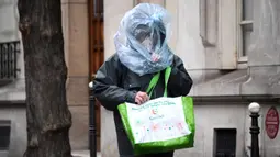 Seorang pria melindungi wajahnya dengan kantong plastik saat diberlakukannya lockdown untuk menghentikan penyebaran COVID-19 di jalanan Paris pada 21 Maret 2020. Masker dijadikan masyarakat pilihan untuk mencegah penyebaran virus corona yang terus meningkat di seluruh dunia. (FRANCK FIFE/AFP)