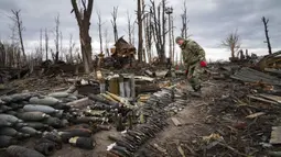 Seorang pencari ranjau dari Kementerian Dalam Negeri Ukraina mengumpulkan selongsong peluru, granat, dan perangkat lain yang belum meledak di Hostomel, dekat Kiev, Ukraina, 18 April 2022. (AP Photo/Efrem Lukatsky)