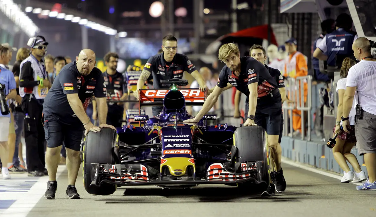 Mobil Toro Rosso Formula 1 yang dibawa Max Verstappen diperiksa saat sesi latihan F1 Grand Prix di Sirkuit Marina Bay, Singapura (17/9/2015). Kabut asap yang menyelimuti sirkuit tak menyurutkan pembalap untuk tetap melakukan pemanasan. (REUTERS/Tim Chong)