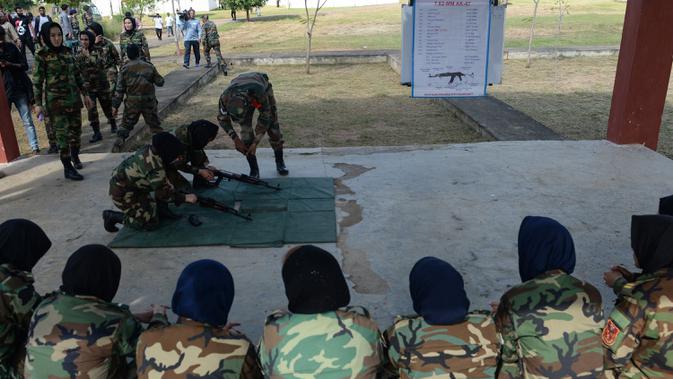 Sejumlah kadet tentara wanita Afghanistan memperhatikan pengarahan pelatih yang mengajarkan cara menyiapkan senapan sebelum menembak saat mengikuti program latihan militer di Akademi Pelatihan Perwira di Chennai, India (12/12/2019). (AFP/Arun Sankar)