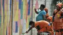 Petugas dari Penanganan Prasarana dan Sarana Umum (PPSU) membuat mural pada tembok yang berada di pinggir Jalan Landasan Pacu, Kemayoran, Jakarta, Rabu (11/7). (Merdeka.com/Iqbal S. Nugroho)